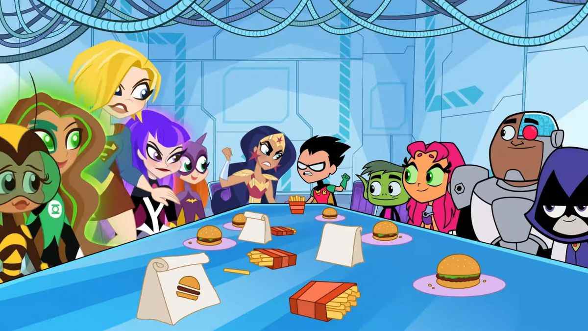 Les Teen Titans et les DC Super Hero Girls sont assises autour d'une table avec des hamburgers et des frites.