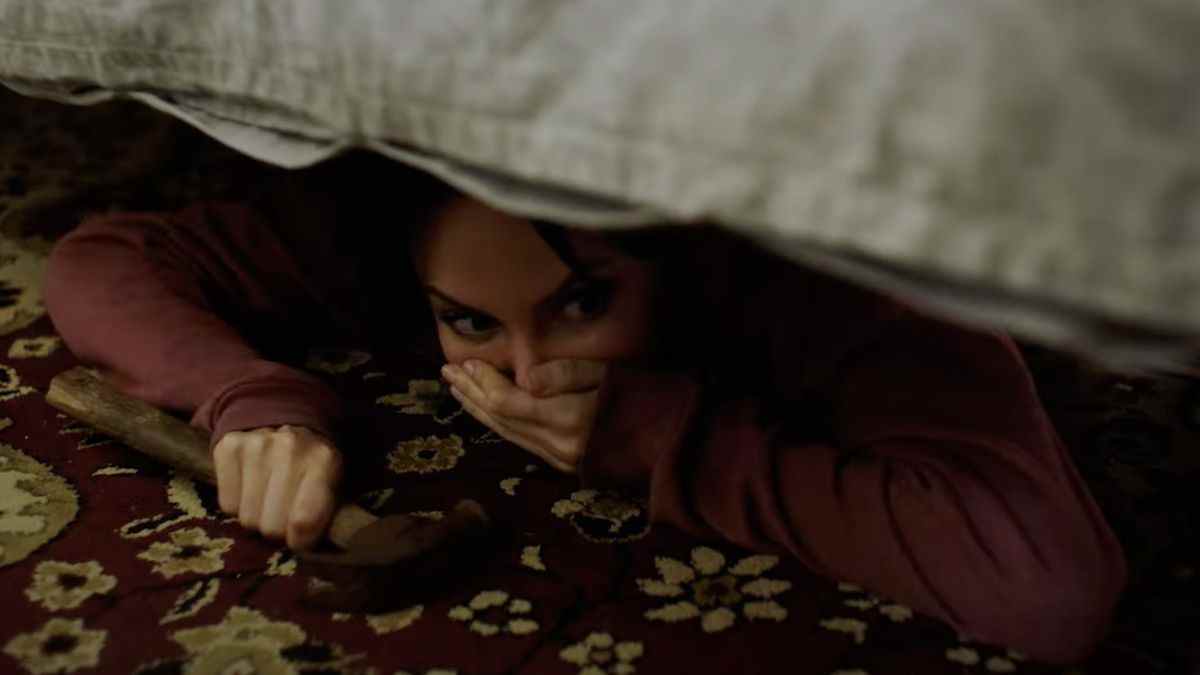 Yulia Klass dans le rôle d'Alys se cachant sous un lit avec un marteau à la main dans Captors.