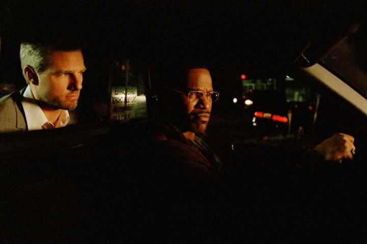 Tom Cruise est assis derrière Jamie Foxx dans un taxi dans Michael Mann's Collateral.