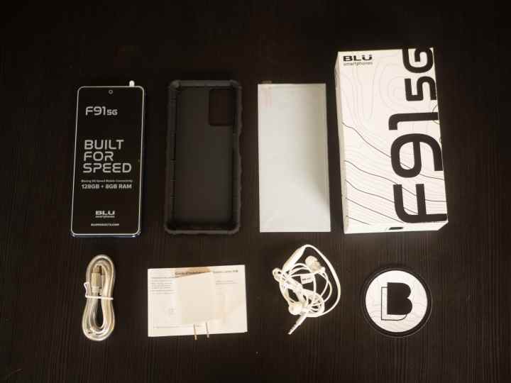 Contenu du smartphone Blu F91 5G posé sur une table en bois noire
