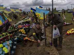 Deux gardes nationaux visitent la tombe d'un soldat décédé au cimetière de Kharkiv, dans l'est de l'Ukraine, dimanche 22 mai 2022.