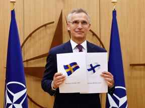 Le secrétaire général de l'OTAN, Jens Stoltenberg, pose avec les documents de candidature présentés par l'ambassadeur de Finlande auprès de l'OTAN, Klaus Korhonen, et l'ambassadeur de Suède auprès de l'OTAN, Axel Wernhoff, lors d'une cérémonie marquant la demande d'adhésion de la Suède et de la Finlande à Bruxelles, le 18 mai 2022.