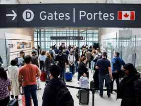 Les voyageurs se pressent dans la file d'attente de sécurité dans la salle des départs au début du long week-end de la fête de Victoria à l'aéroport international Pearson de Toronto à Mississauga, en Ontario, le vendredi 20 mai 2022.