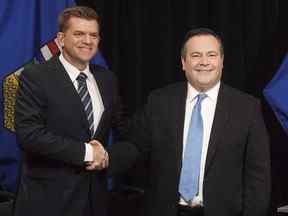Le chef de l'Alberta Wildrose, Brian Jean, et le chef du PC de l'Alberta, Jason Kenney, se serrent la main après avoir annoncé un accord d'unité entre les deux partis à Edmonton le 18 mai 2017.