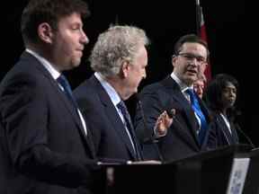 Le candidat à la chefferie du Parti conservateur, Pierre Poilievre, fait un geste vers Jean Charest alors que Roman Baber, à gauche, Scott Aitchison et Leslyn Lewis, à droite, regardent lors d'un débat à la conférence Canada Strong and Free Network, à Ottawa, le jeudi 5 mai 2022.