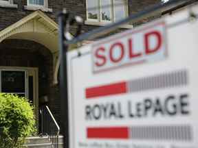 Un agent immobilier à vendre affiche à l'extérieur d'une maison qui a été vendue à Toronto.