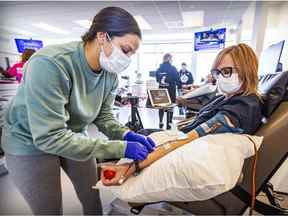 L'infirmière auxiliaire Melissa Robles connecte le tube à la donneuse Nathalie Drouin-Courtois, qui faisait un don de plasma à une clinique de sang d'Héma-Québec à Kirkland.