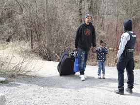 Des demandeurs d'asile entrent au Canada depuis la frontière américaine près d'un point de contrôle sur le chemin Roxham près de Hemmingford, Québec, Canada, le 24 avril 2022.