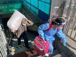 Les voyageurs transportant des bagages quittent une station de métro le premier jour de la reprise de certaines parties des services de métro de la ville à Shanghai, en Chine, le 22 mai 2022.