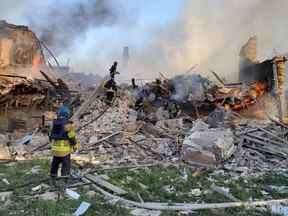 L'équipe d'urgence s'occupe d'un incendie près de débris en feu, après qu'un bâtiment scolaire a été touché à la suite d'un bombardement, dans le village de Bilohorivka, Luhansk, Ukraine, le 8 mai 2022.