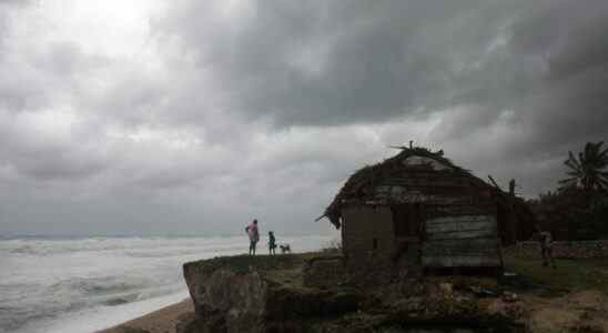 People stand in front of their home overlooking the sea as Tropical Storm Isaac approaches in Barahona, Dominican Republic, Friday, Aug. 24, 2012. Tropical Storm Isaac strengthened slightly as it spun toward the Dominican Republic and vulnerable Haiti on Friday, threatening to bring punishing rains but unlikely to gain enough steam to strike as a hurricane. (AP Photo/Ricardo Arduengo)