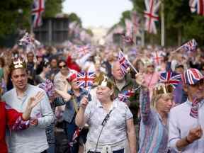Les gens brandissent des drapeaux Union Jack, alors qu'ils se rassemblent sur le centre commercial avant un concert devant le palais de Buckingham lors des célébrations du jubilé de platine de la reine Elizabeth en Grande-Bretagne, à Londres, en Grande-Bretagne, le 4 juin 2022. REUTERS/Henry Nicholls