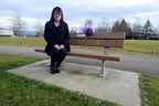 Carol Todd est assise sur un banc commémoratif pour sa fille Amanda, qui s'est suicidée après avoir été victime de cyberintimidation.  Un étranger a récemment décoré le banc avec les fleurs violettes préférées d'Amanda pour son anniversaire.