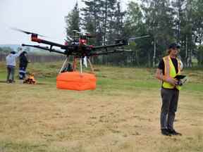 Un travailleur d'AltoMaxx, basé à Toronto, utilise un drone pour fouiller le site de l'ancien pensionnat de Fort Alexander dans la Première Nation de Sagkeeng à la recherche de tombes anonymes, tandis qu'un feu sacré brûle en arrière-plan.