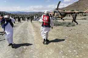 Cette photographie prise le 22 juin 2022 et reçue avec l'aimable autorisation de l'agence de presse gouvernementale afghane Bakhtar montre des soldats et des responsables de la Société afghane du Croissant-Rouge près d'un hélicoptère dans une zone touchée par un tremblement de terre dans le district afghan de Gayan, dans la province de Paktika.  (Photo de l'agence de presse Bakhtar / AFP)