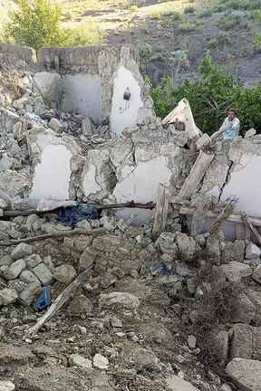 Cette photographie prise le 22 juin 2022 et reçue avec l'aimable autorisation de l'agence de presse gouvernementale afghane Bakhtar montre un homme debout à côté d'une maison en terre effondrée à la suite d'un tremblement de terre dans le district de Gayan, dans la province de Paktika.  (Photo de l'agence de presse Bakhtar / AFP)