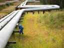 Un homme travaille à côté de pipelines à l'usine Foster Creek de Cenovus Energy en Alberta.