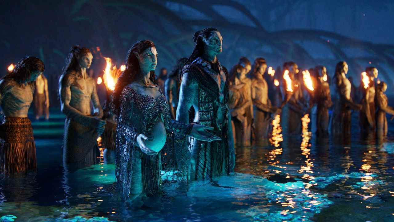 Jake et Neytyri se tiennent dans l'eau avec d'autres Na'vi dans Avatar : La Voie de l'Eau.