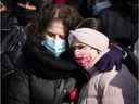 Salema tient une rose et sa fille de 11 ans, Dania, alors qu'elles écoutent des orateurs lors d'une veillée pour Meriem Boundaoui à Montréal le 14 février 2021.
