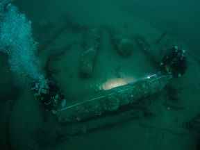 Les frères Julian Barnwell et Lincoln Barnwell mesurent un canon sous l'eau, depuis l'épave du HMS Gloucester, qui a coulé il y a 340 ans alors qu'il transportait le roi d'Angleterre, James Stuart, et a été découvert au large de Norfolk, en Grande-Bretagne, le 25 juillet 2018.