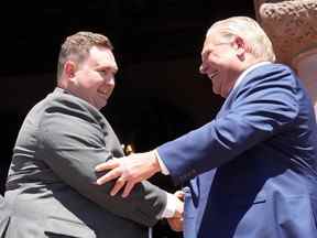 Le nouveau ministre de la Citoyenneté et du Multiculturalisme de l'Ontario, Michael Ford, serre la main de son oncle, le premier ministre Doug Ford, lors d'une cérémonie d'assermentation à Queen's Park, à Toronto, le 24 juin 2022.