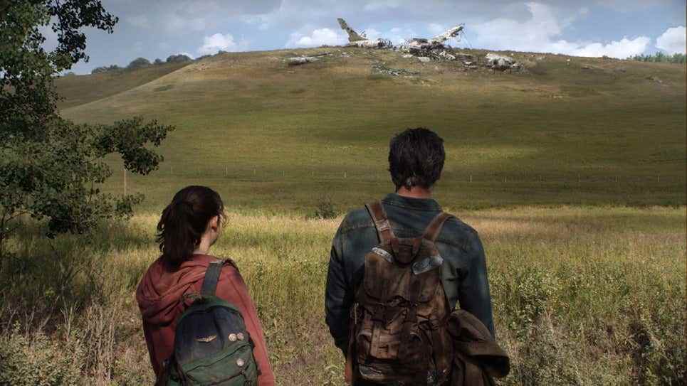 Bella Ramsey (comme Ellie) et Pedro Pascal (comme Joel) sont vus de dos alors qu'ils regardent un avion écrasé dans la série The Last of Us HBO
