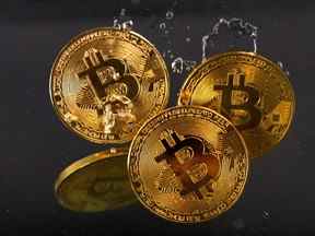 Des jetons souvenirs représentant la crypto-monnaie Bitcoin plongent dans l'eau.