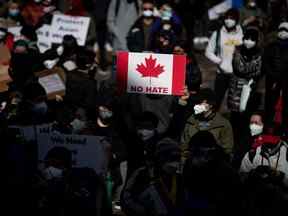 Une personne tient une pancarte du drapeau canadien avec les mots 