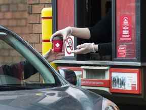 Un employé de Tim Hortons distribue du café depuis une fenêtre de service au volant à un client de Mississauga, en Ontario, le 17 mars 2020.