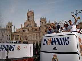 Les joueurs du Real Madrid célèbrent avec leur trophée alors qu'ils saluent d'un bus à toit ouvert lors d'un défilé dans les rues de Madrid le 29 mai 2022, un jour après avoir battu Liverpool en finale de l'UEFA Champions League à Paris.  (Photo de GABRIEL BOUYS/AFP via Getty Images)