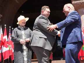Le ministre de la Citoyenneté et du Multiculturalisme, Michael Ford, serre la main du premier ministre Doug Ford sous le regard de la lieutenante-gouverneure de l'Ontario Elizabeth Dowdeswell, lors de la cérémonie d'assermentation à Queen's Park à Toronto le 24 juin 2022.