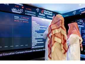 Les visiteurs regardent les informations sur les cours des actions affichées sur un écran numérique à l'intérieur de la Bourse saoudienne, également connue sous le nom de Tadawul, à Riyad, en Arabie saoudite, le mardi 10 avril 2018. Les investisseurs étrangers ont acheté plus d'actions saoudiennes en mars que jamais auparavant en prévision du passage du royaume au statut de marché émergent.  Photographe : Abdulrahman Abdullah/Bloomberg