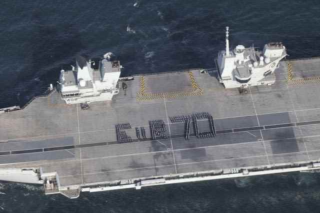 Plus de 300 marins de la Royal Navy épelant une salutation géante du jubilé de platine à la reine sur le pont d'envol du porte-avions HMS Queen Elizabeth 
