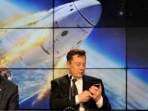 Elon Musk regarde son téléphone portable au Kennedy Space Center à Cap Canaveral, en Floride