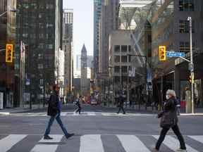 Les navetteurs du matin traversent Yonge Street à Bay Street dans le quartier financier de Toronto.