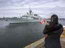 Une femme prend une photo alors que le NCSM Halifax quitte Halifax le 19 mars.