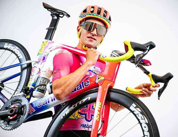 Une photo de Ruben Guerreiro portant son kit cycliste laid Palace X Rapha avec son vélo laid Palace X Rapha.