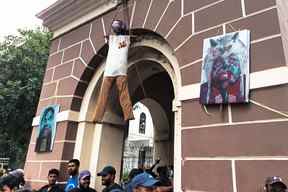 Des militants se tiennent sous l'effigie du président sri-lankais Gotabaya Rajapaksa, suspendu à une tour de l'horloge près de sa résidence officielle, à Colombo le 10 juillet 2022.