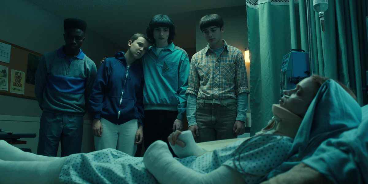 Lucas, Eleven, Mike et Will debout et regardant Max dans un lit d'hôpital