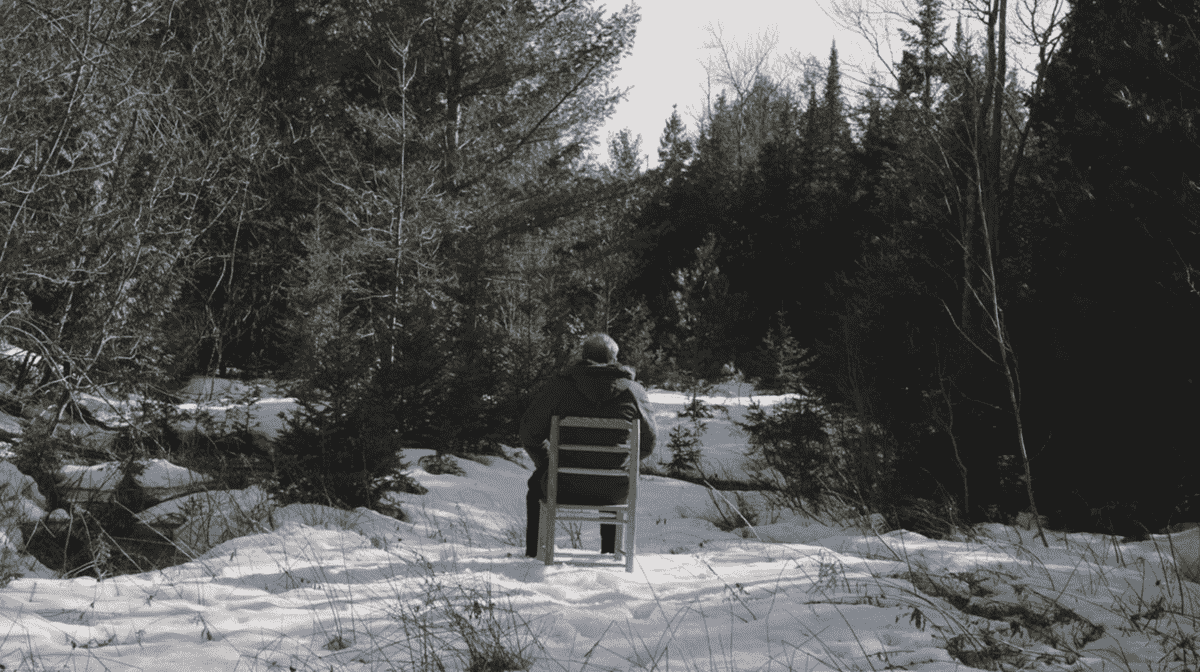 Joe Pera assis sur une chaise dans les bois