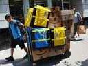 Un employé d'Amazon.com Inc. tire un chariot de colis à livrer à New York. 
