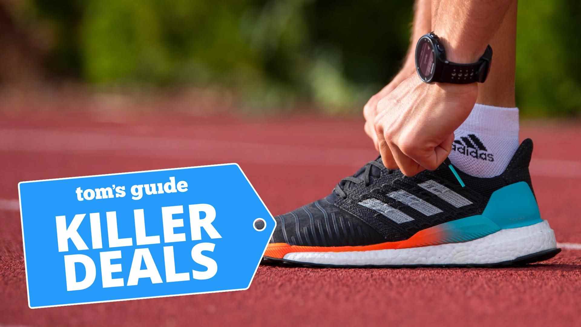 Une photo d'un coureur accroupi pour attacher les lacets d'une paire de chaussures Adidas