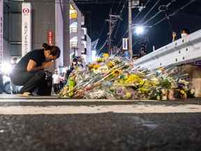 Une femme réagit devant un mémorial de fortune où les gens déposent des fleurs sur les lieux devant la gare de Yamato-Saidaiji à Nara où l'ancien Premier ministre japonais Shinzo Abe a été abattu plus tôt dans la journée du 8 juillet 2022.