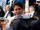 Le premier ministre Justin Trudeau accroche son manteau au dossier de sa chaise en attendant le début de la cinquième séance de travail avec des représentants des Sept nations riches (G7) et des invités de sensibilisation sur 