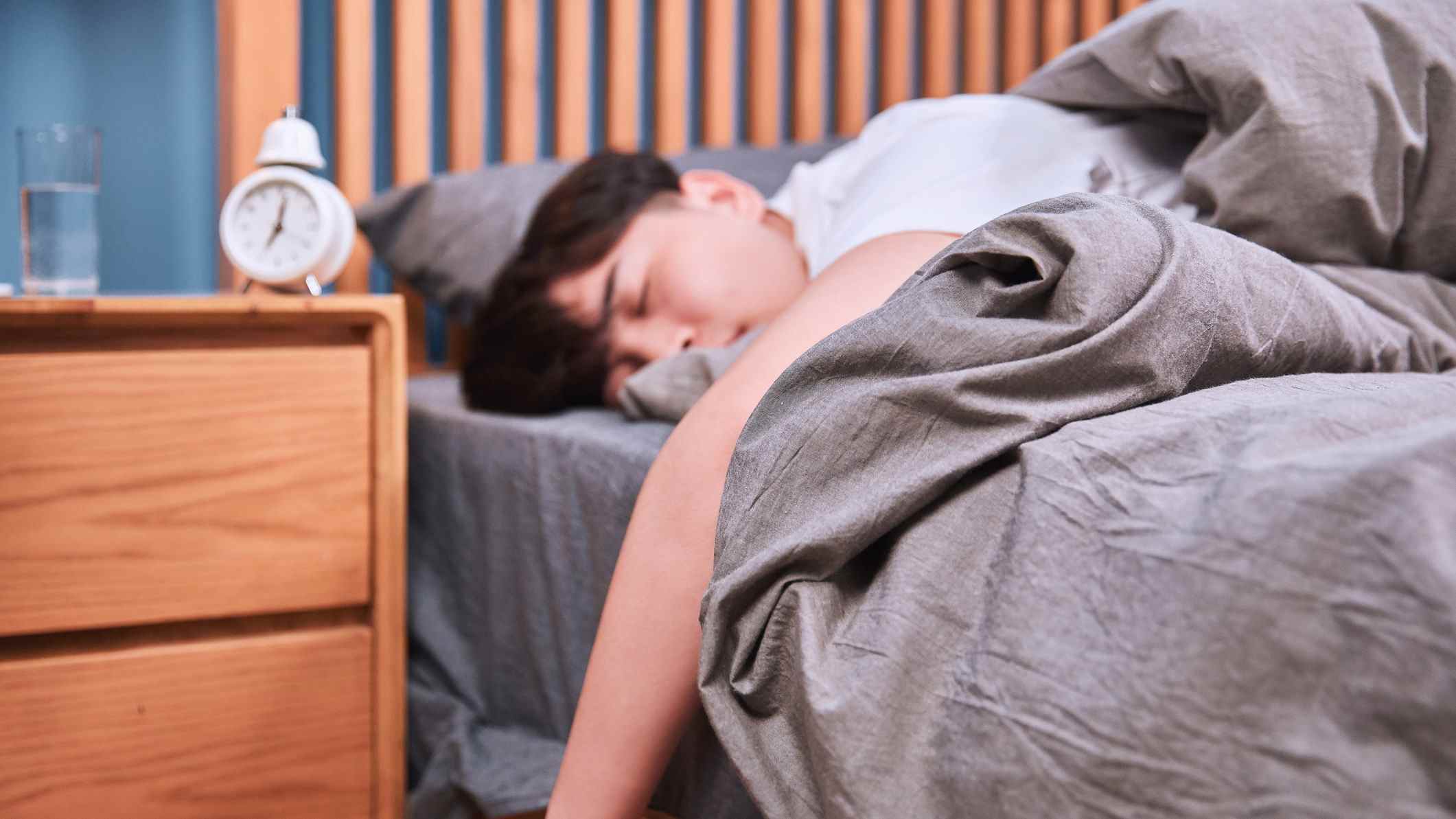 Un homme dort bien après son alarme de sept heures du matin et n'arrive pas à se débarrasser de sa somnolence