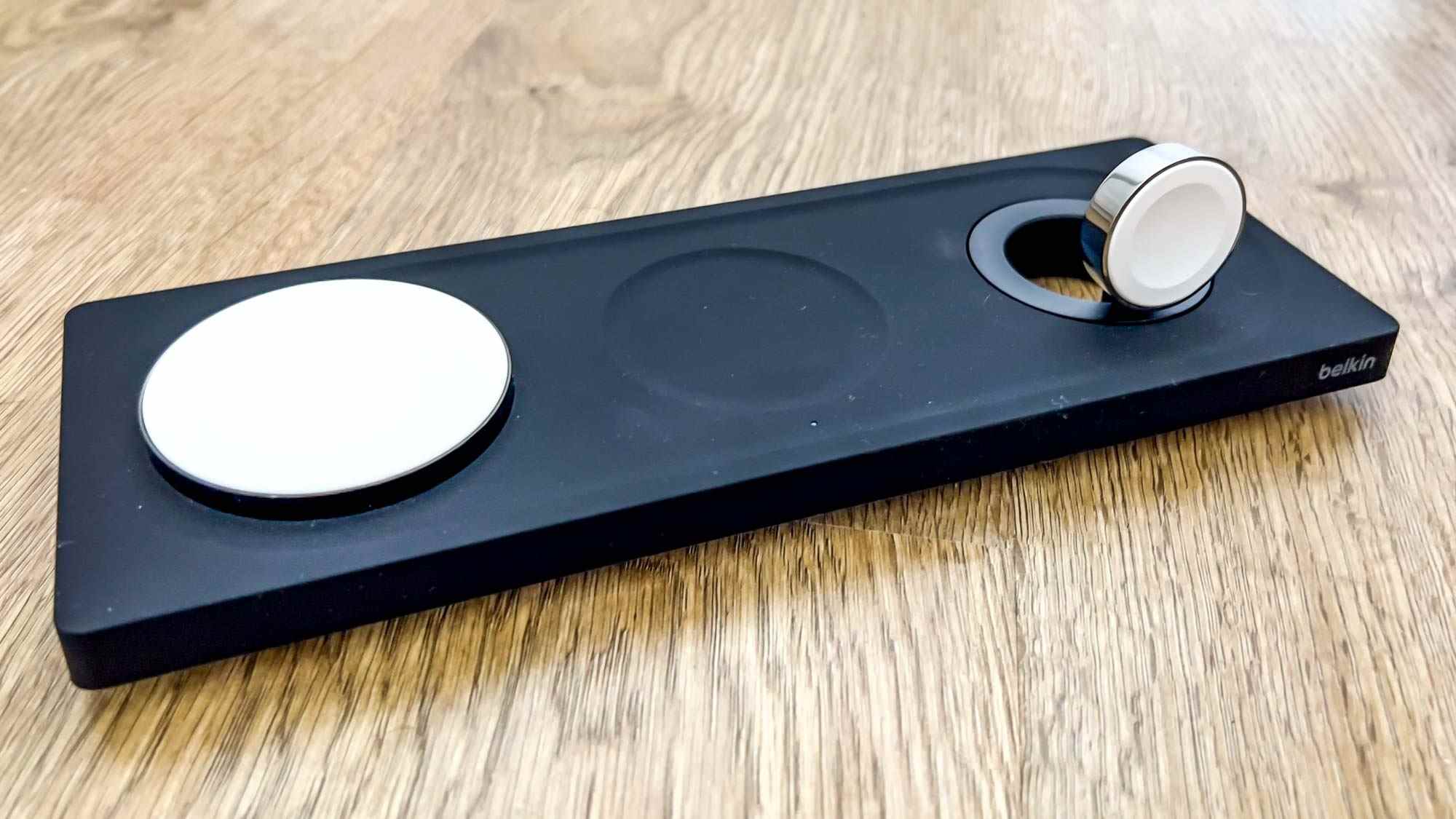 Le chargeur sans fil Belkin BoostCharge Pro 3-en-1 avec MagSafe en noir sur une surface en bois