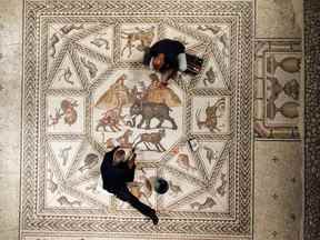 Des ouvriers nettoient une mosaïque restaurée de l'époque romaine après qu'elle a été exposée sur son site d'origine à Lod, aujourd'hui une ville israélienne où un centre archéologique a été inauguré.  REUTERS/Amir Cohen