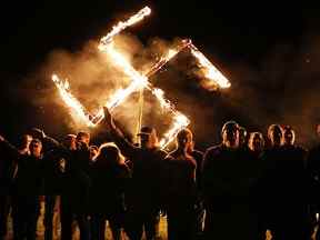Des membres du National Socialist Movement, l'un des plus grands groupes néonazis aux États-Unis, tiennent une croix gammée en feu après un rassemblement le 21 avril 2018 à Draketown, en Géorgie.  (Photo de Spencer Platt/Getty Images)