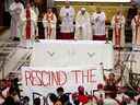 Des autochtones tiennent une banderole de protestation alors que le pape François célèbre la messe au Sanctuaire national de Sainte-Anne-de-Beaupré le 28 juillet 2022.