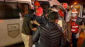 Les autorités mexicaines aident un migrant blessé à monter dans un véhicule de l'Institut national des migrations (INM) après avoir été secouru avec d'autres migrants abandonnés à l'intérieur d'une caravane, dans la ville d'Acayucan, dans l'État de Veracruz, au Mexique, le 27 juillet 2022.
